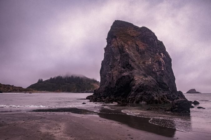 Large boulder rock on beach on cloudy day