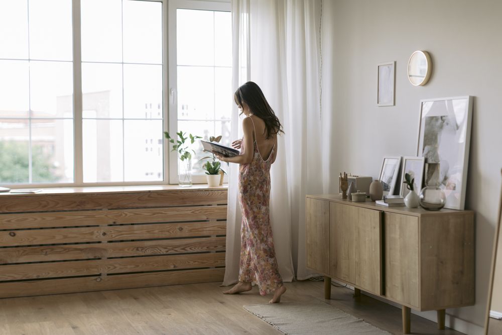 Young woman at home holding a book near a window