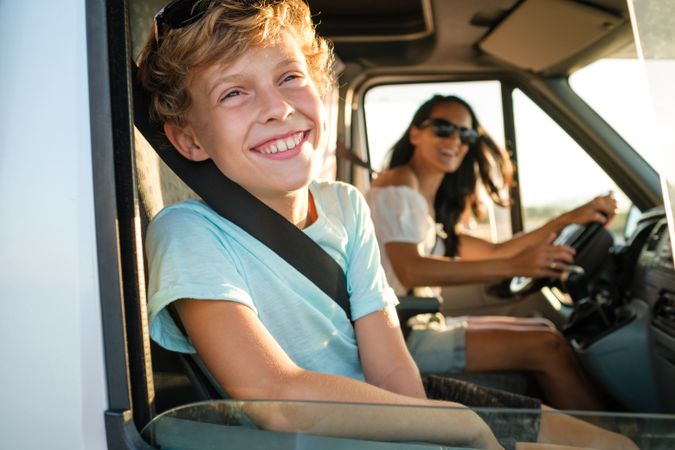 Joyful mother and kid enjoying summer journey by car