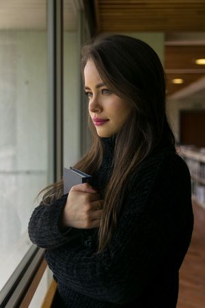 Woman with book looking out window