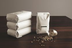 Pouches of coffee beans with blank label with spilled glass of whole beans