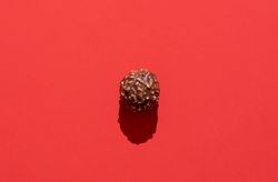 Chocolate truffle minimalist on a red background in bright light