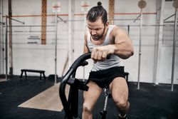 Healthy man on exercise bike in gym