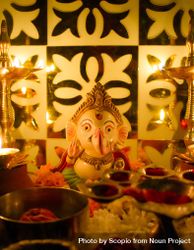 Ganesh figurine surrounded by lit diyas and flowers 5zm9A0
