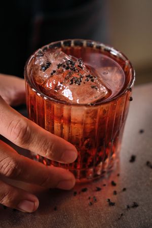 Anonymous bartender serving cocktail with ice cubes