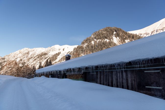 Mountain cabin covered in snow and the Bavarian Alps in the background.