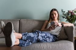 Woman chatting on smartphone on sofa at home