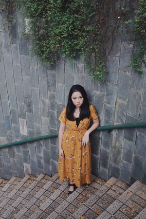 Asian woman in orange dress standing on stairs