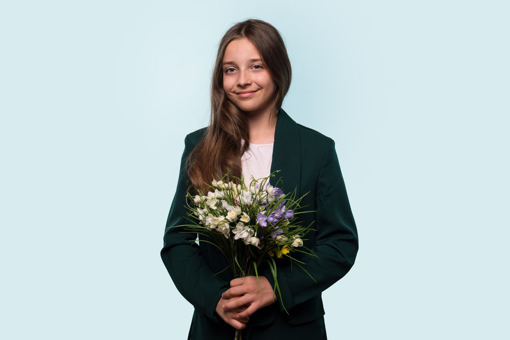 Teen girl holding bouquet of flowers, wearing blazer