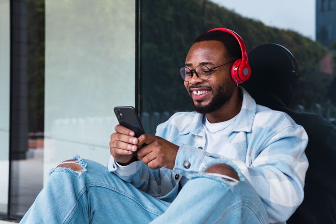 Cheerful Black man with smartphone listening to music