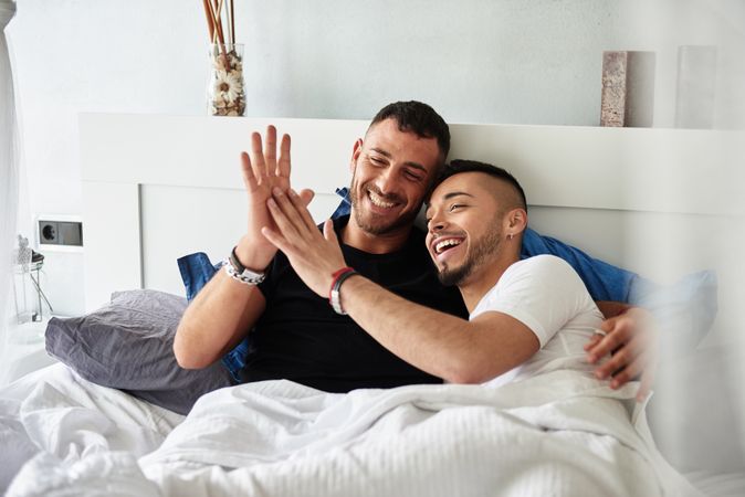 Smiling gay couple hugging on bed