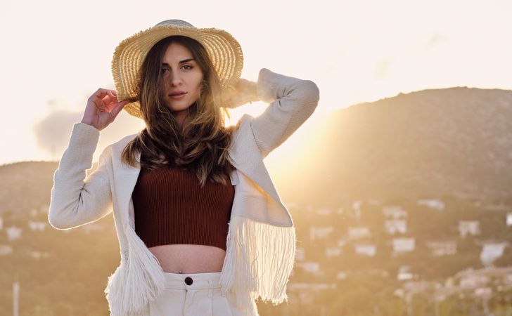A long hair fashion model with a hat at the beach at sunset in a summer day