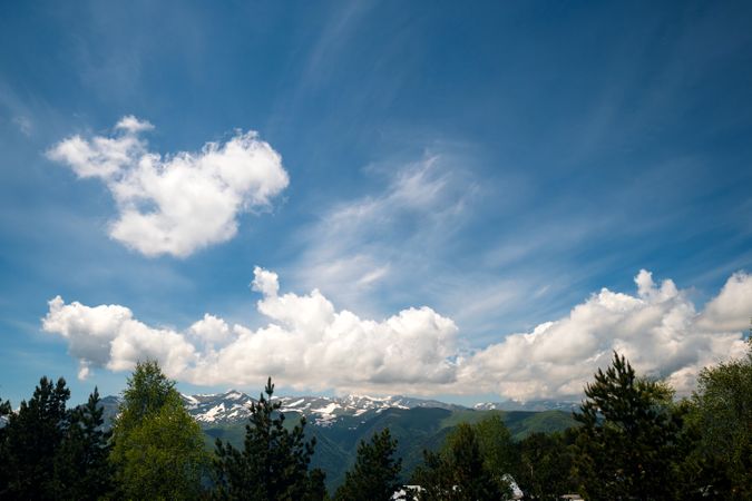 Snow-capped mountains beneath blue sky with clouds.