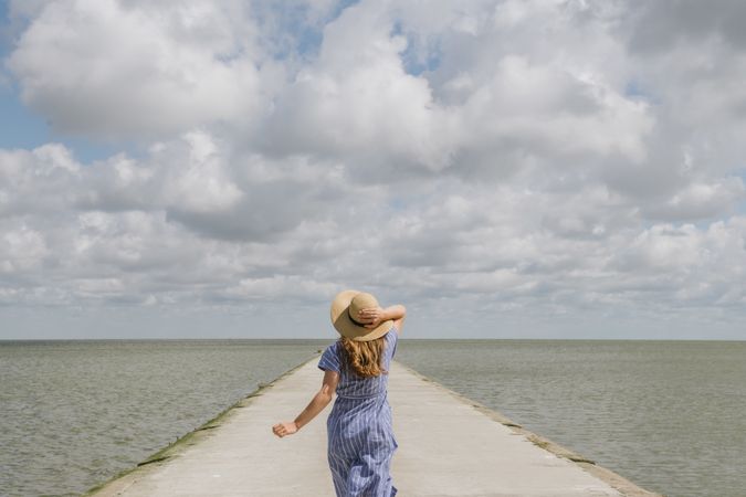 Young woman running on sea wharf