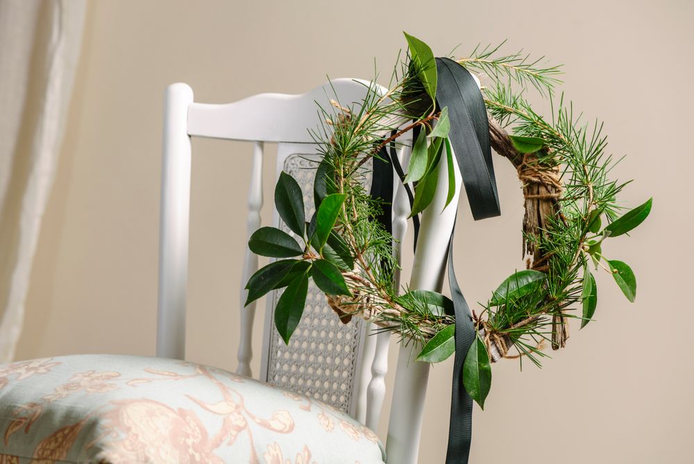 Christmas green wreath hanging on the chair, branches of pine and natural plants