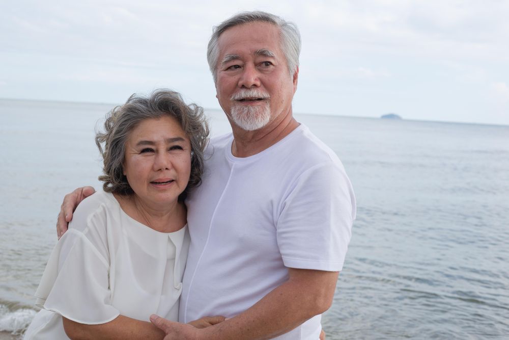 Mature Asian couple holding each other at the beach