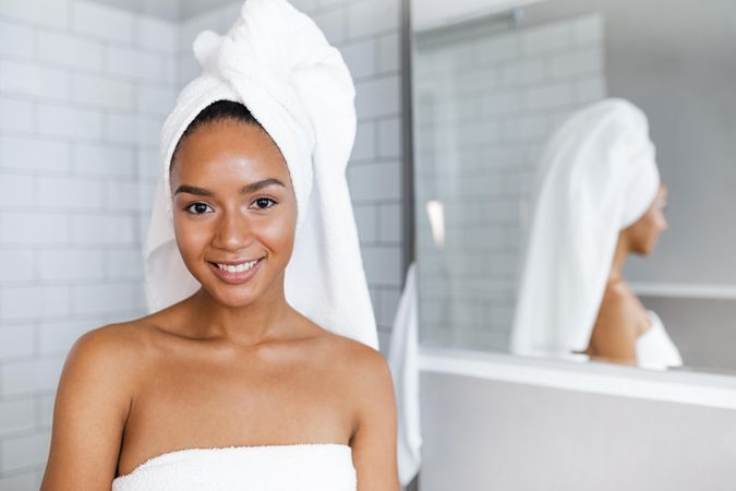Fresh faced Black woman in towels after a shower in bright bathroom