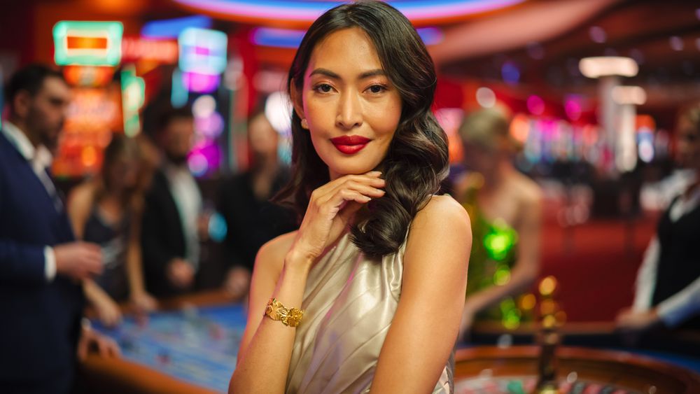Portrait of a Sophisticated Asian Woman in a Stunning Dress Posing, Smiling, Looking at Camera in a Glamorous Casino