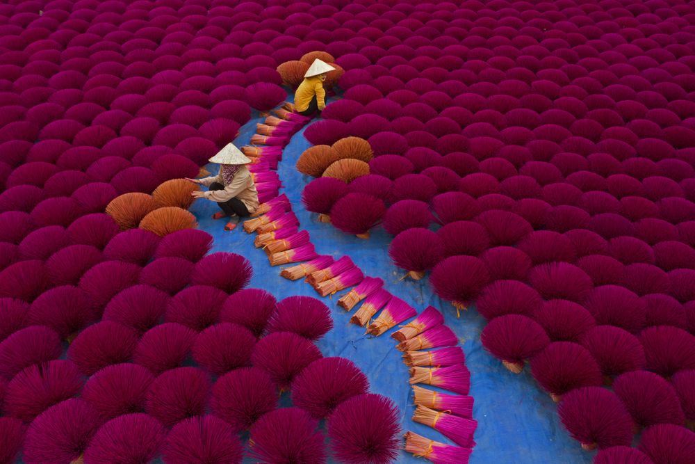 Vietnamese workers sit surrounded by thousands of incense sticks in Quang Phu Cau