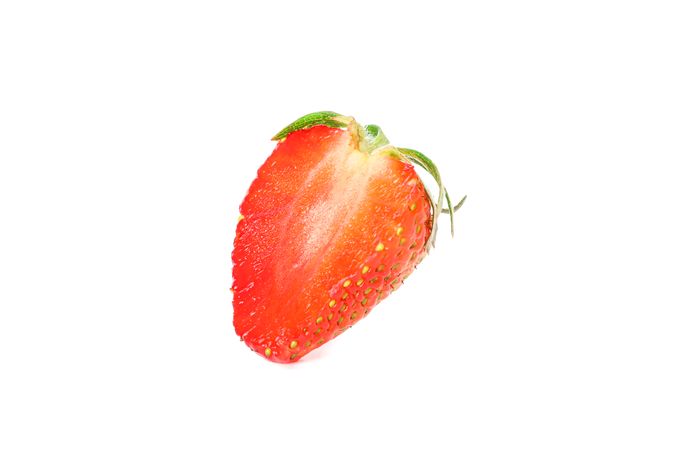 Half of strawberry isolated on light background. Summer sweet fruits and berries