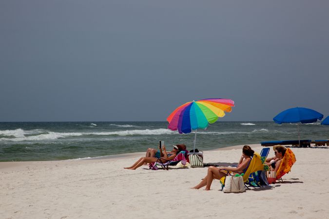 Young women relaxing on beach with umbrella at Gulf Coast of Alabama