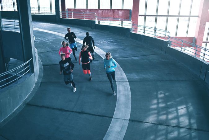Rear view of group of people jogging around a concrete track