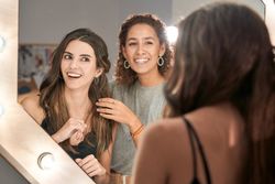 Cheerful women looking in mirror in beauty salon
