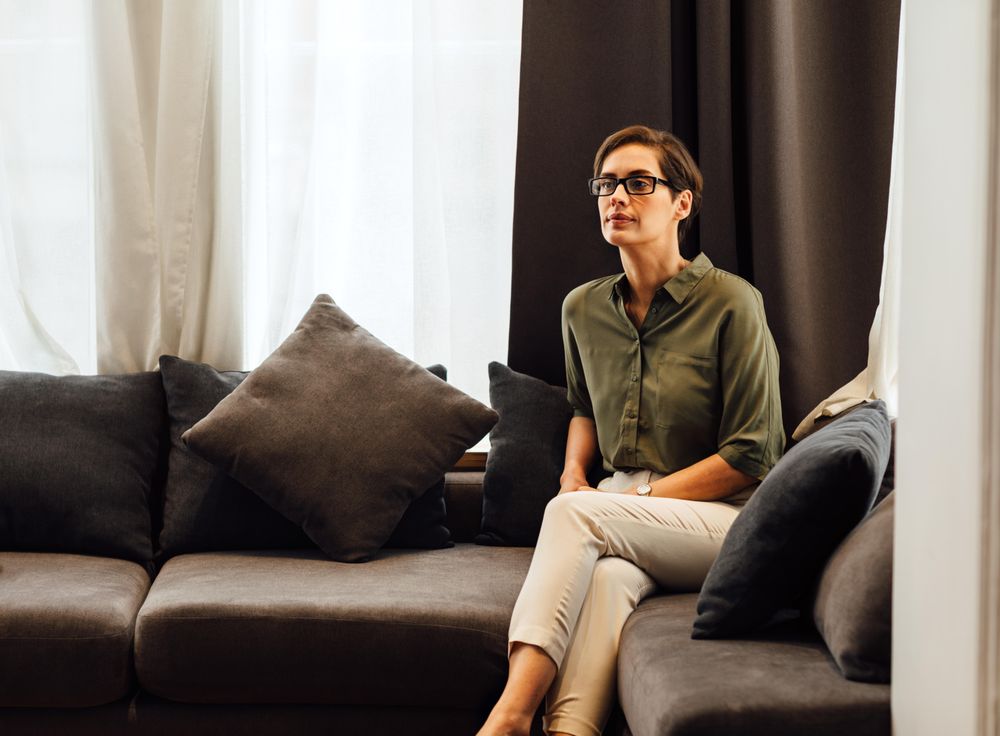 Woman watching TV on sofa with pillows