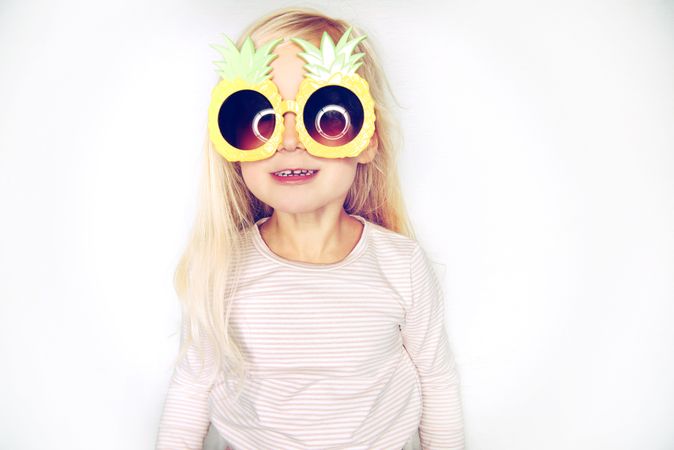 Smiling blonde girl wearing big pineapple sunglasses
