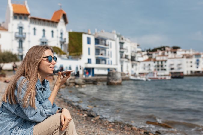 Woman sitting outside at beach talking on smart phone