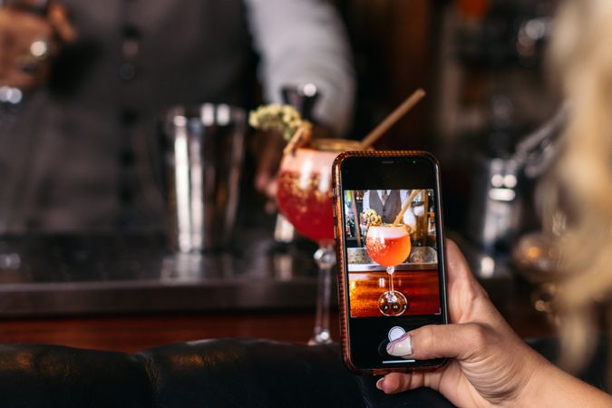 Unrecognizable person taking photos of a cocktail