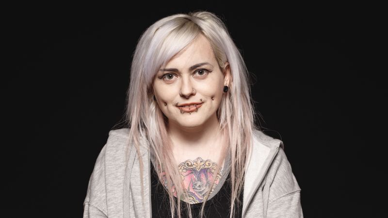 Smiling woman with white hair and tattoo on body looking at camera