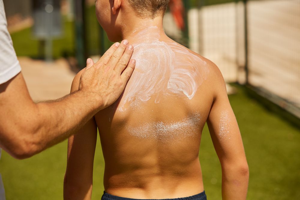 Faceless man applying sun cream on kid