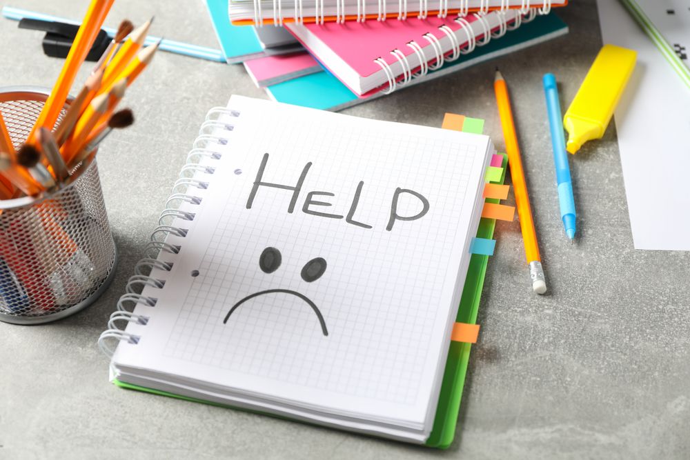 Open notebook with word “Help” with unhappy face