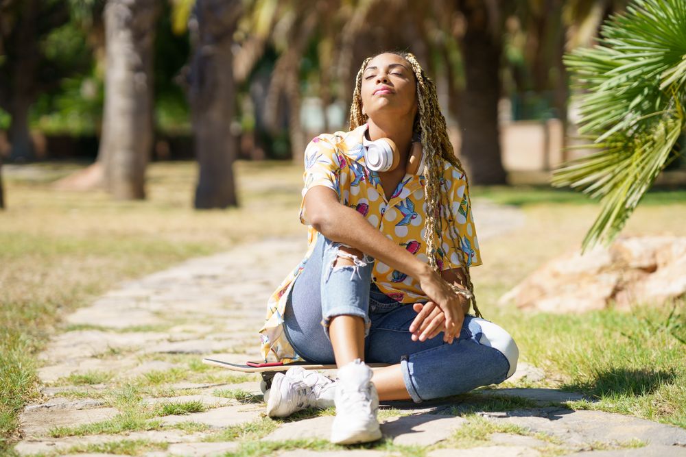 Female sitting on skateboard walkway in park enjoying the sun