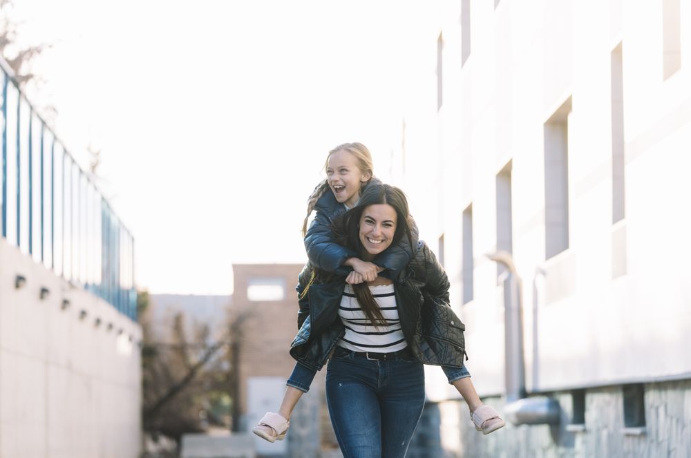 Woman doing young sister piggyback