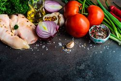 Chicken breasts & vegetables ready for dinner prep on counter with copy space