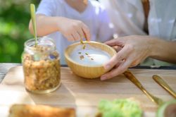 Unrecognizable kid preparing yogurt with granola