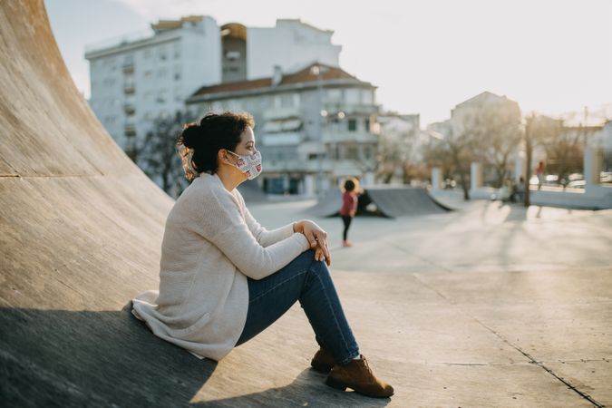 A woman sitting on a ramp in a skatepark