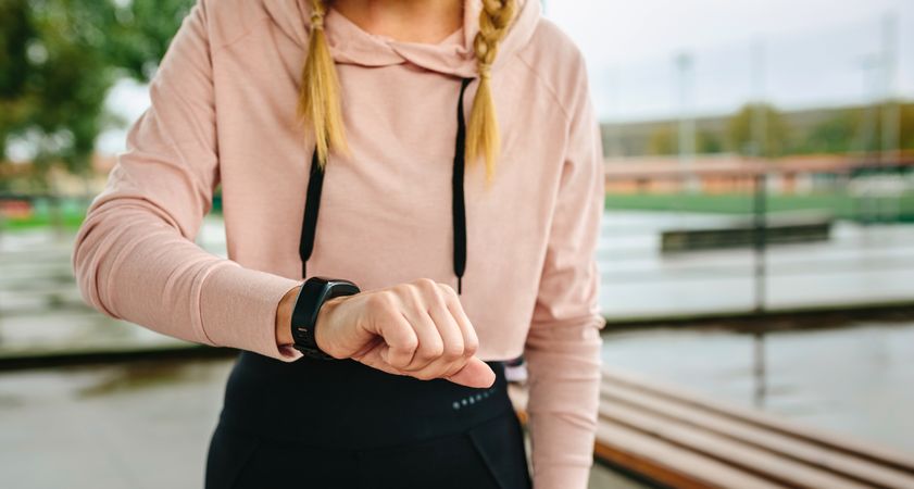 Young sportswoman looking activity bracelet