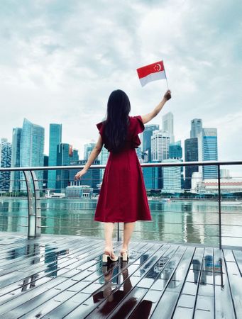 Girl in red dress waving Singapore flag