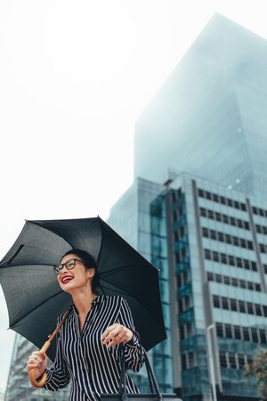 Urban woman smiling on the city street with umbrella