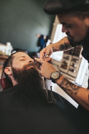 Barber trimming mustache of customer in his salon