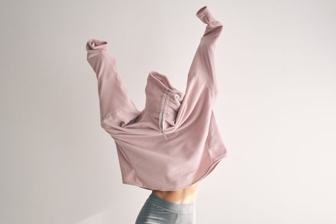 Woman covering face while raising hands up