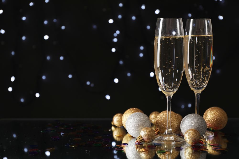 Christmas baubles and champagne glasses on blurred background, copy space