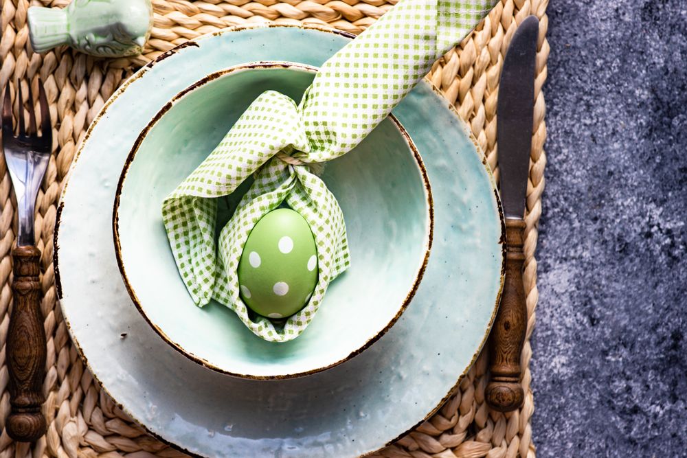 Top view of Easter holiday table setting with pastel egg wrapped in napkin