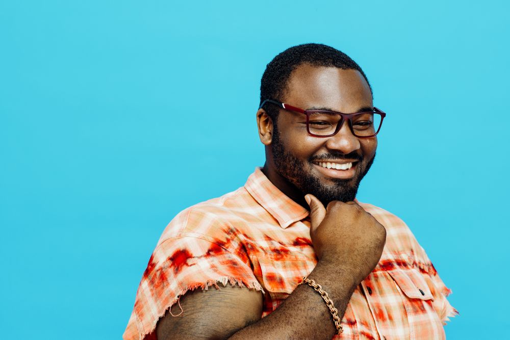 Smiling man in blue studio shoot with hand on chin