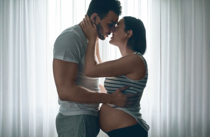 Man embracing and kissing pregnant partner