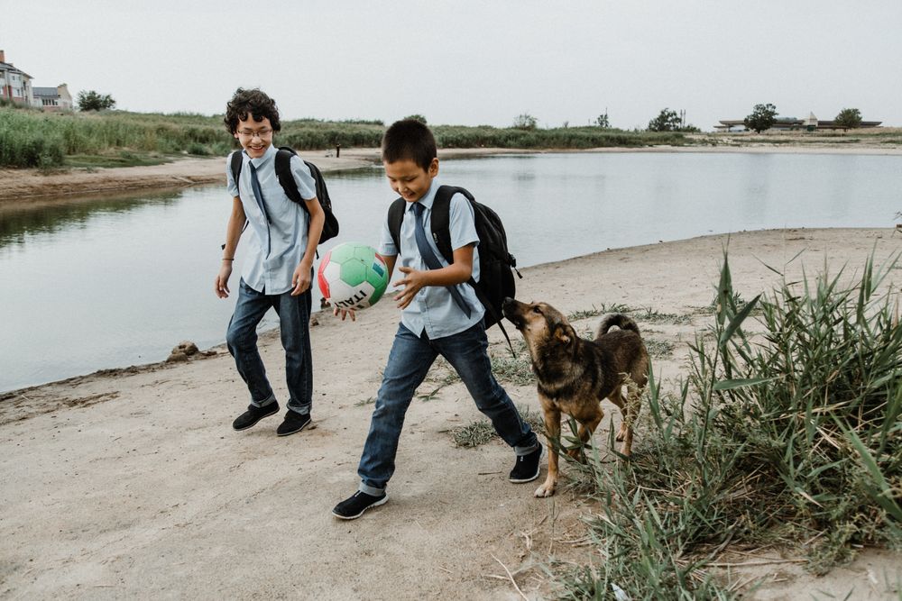Cute boys with ball and dog near river