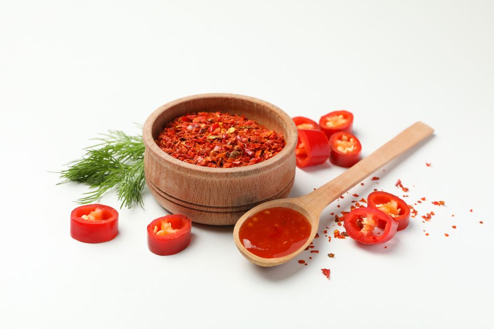 Composition with chilli pepper, spice and sauce on studio background